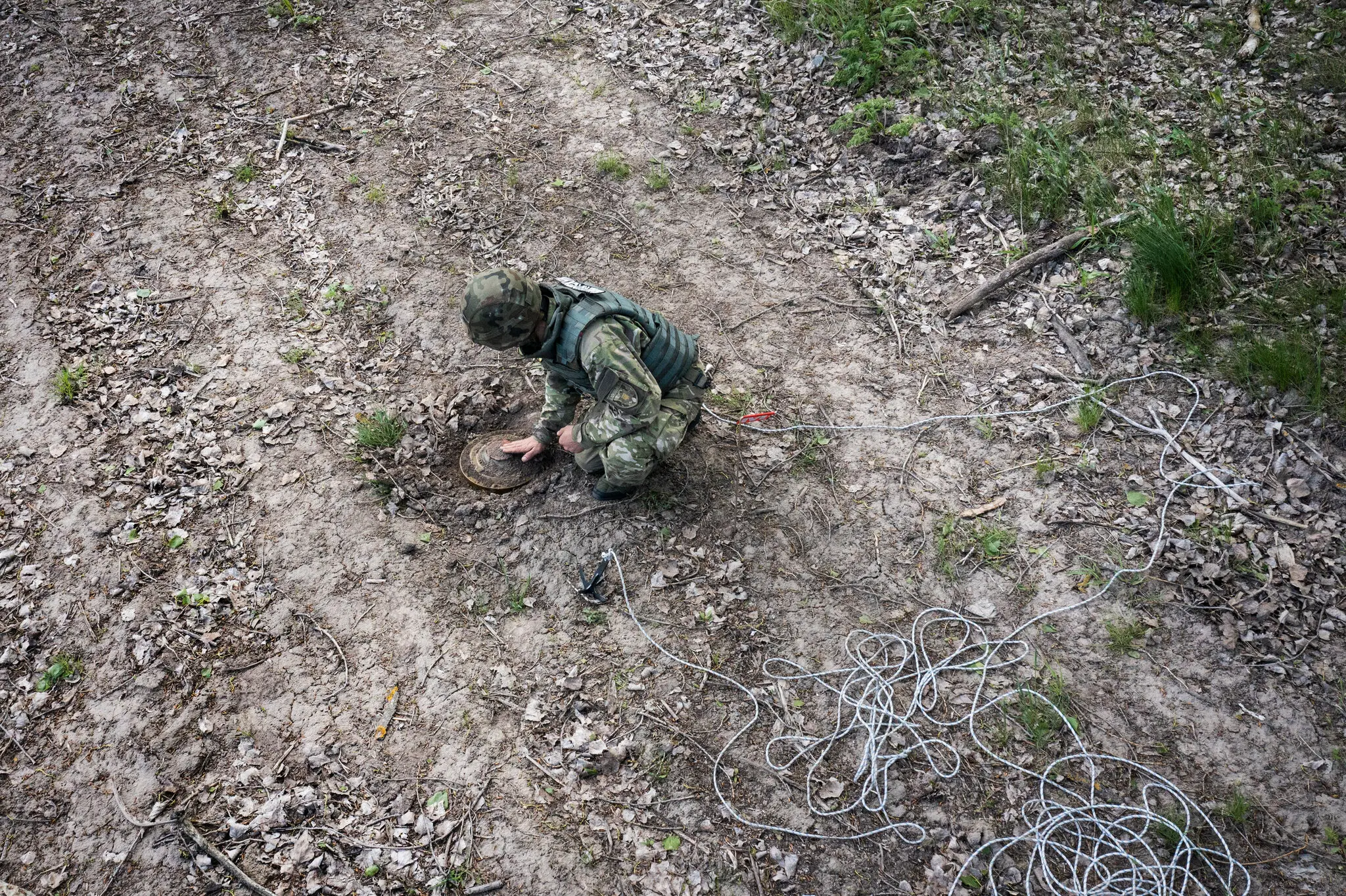 Співробітник вибухотехнічної групи української поліціїготується знешкодити російську міну, знайдену у 2022 році на полі поблизу міста Гоголів.